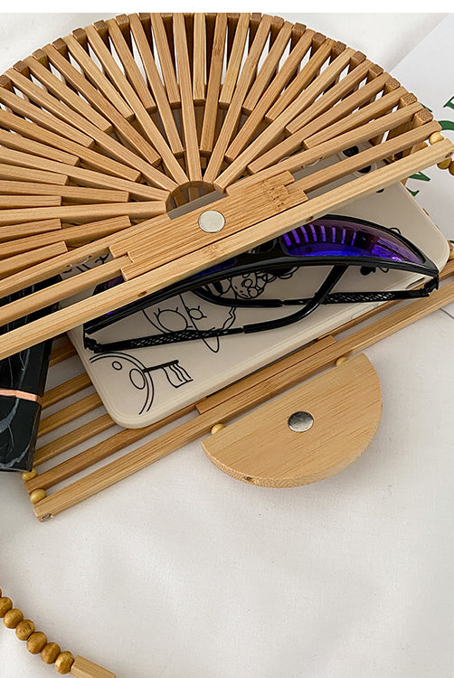 Light brown handbag, made of bamboo. It has a magnet that closes the bag securely. This bag is perfect for your vacation, and can go with any beach outfit. You can use it with or without the strap.