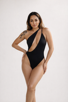 Black One-piece swimwear by Jglam Beachwear modeled on a beach.