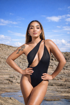 Black One-piece swimwear by Jglam Beachwear modeled on a beach.